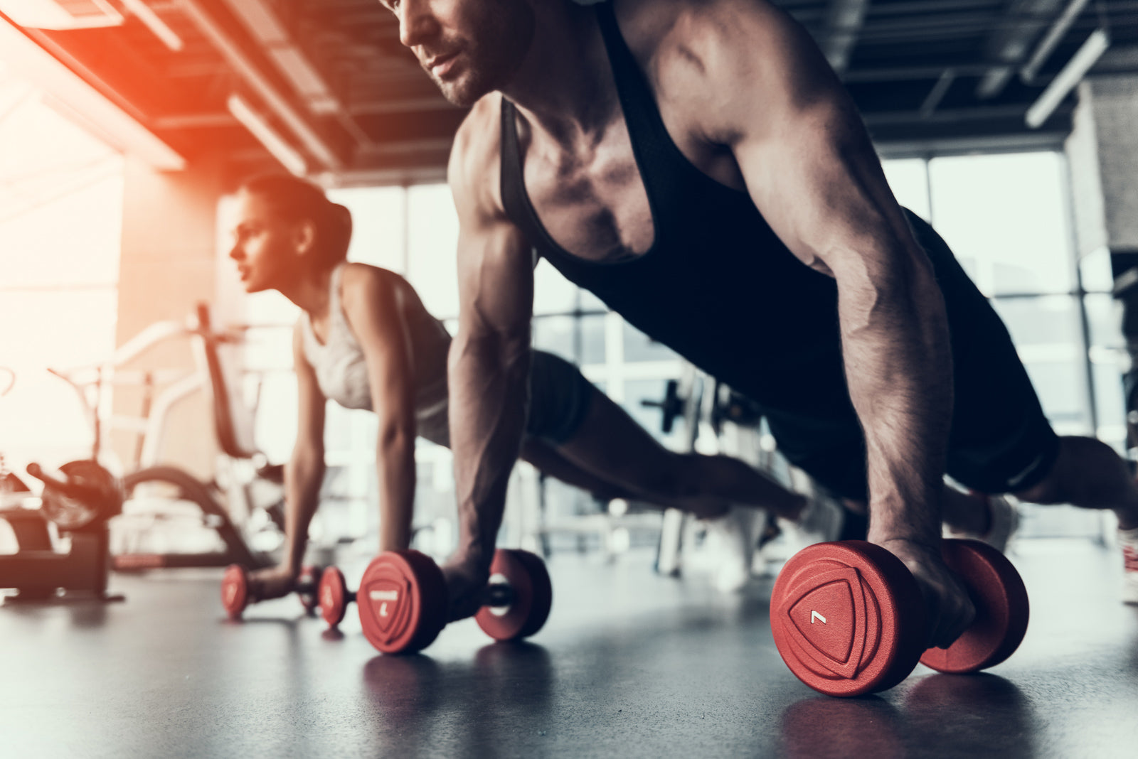 Athlet und Athletin trainieren mit Kurzhanteln – steht für Kraft, Ausdauer und mentale Stärke, inspiriert durch Gym.Cap Produkte.